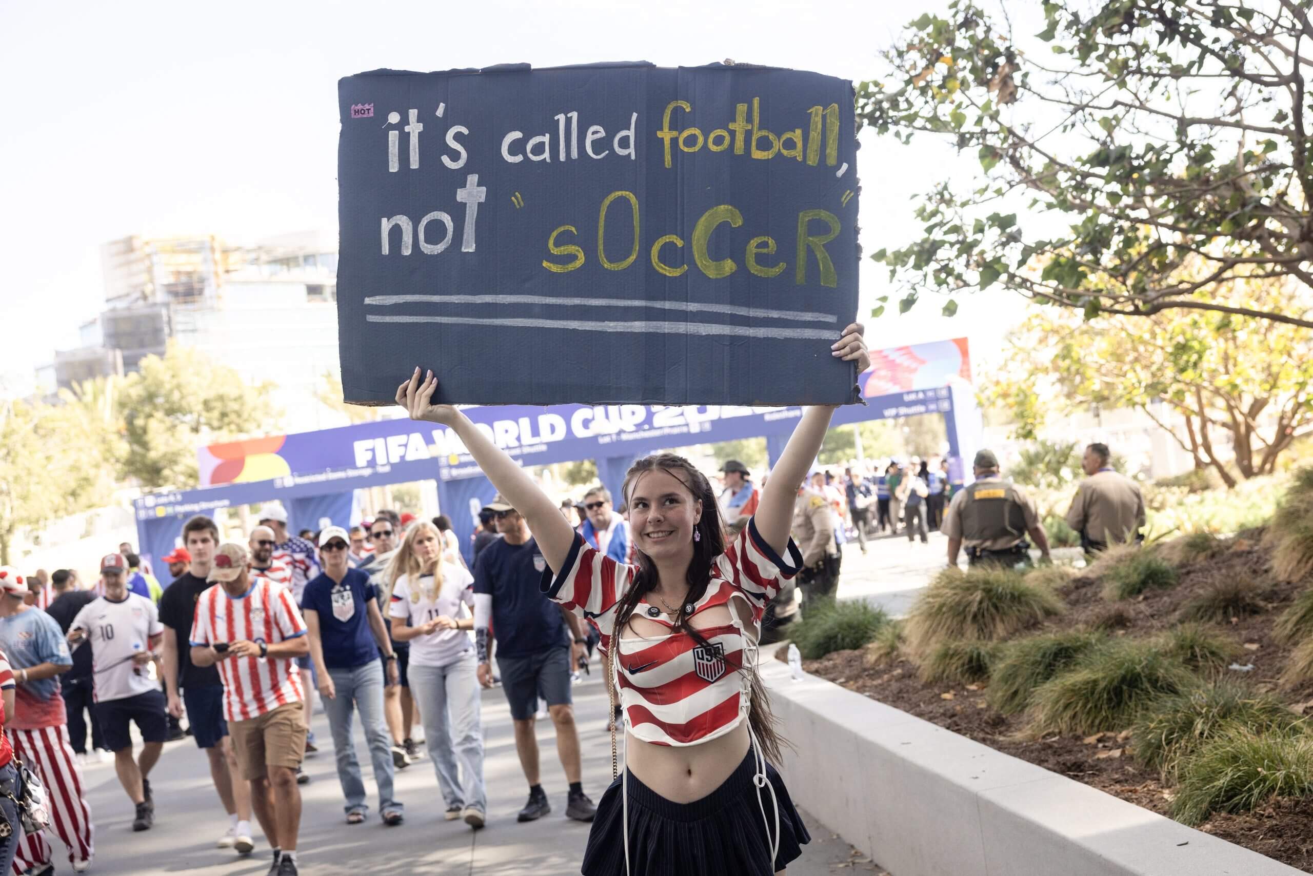 A fan of the USMNT holds up a placard reading 'it's called football, not soccer' outside SoFi Stadium