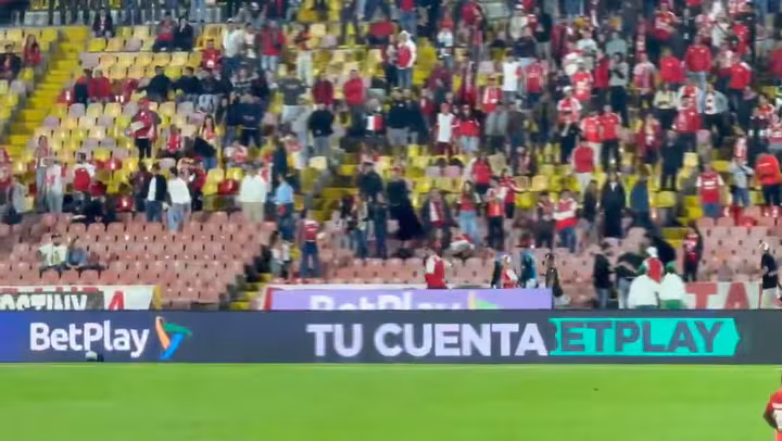 Uno de los registros muestra a hinchas corriendo por un pasillo de la tribuna mientras los jugadores esperaban en el campo de juego