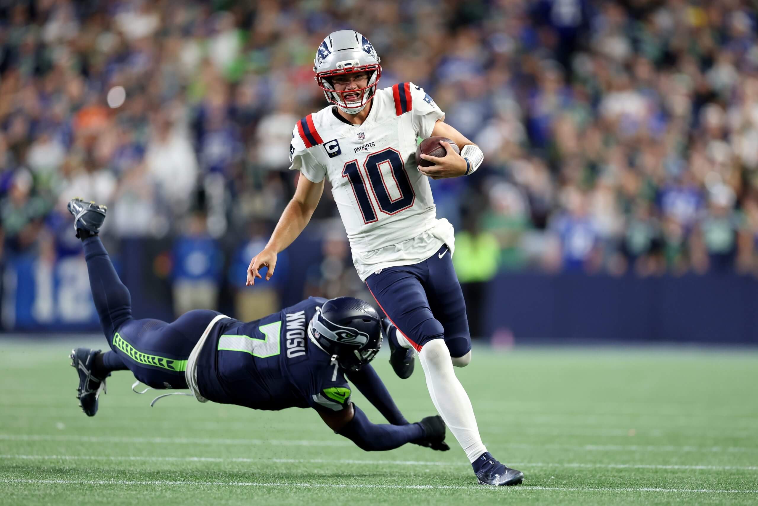 Drake Maye #10 of the New England Patriots runs the ball against Uchenna Nwosu #7 of the Seattle Seahawks during the fourth quarter in the game at Lumen Field on September 09, 2026 in Seattle, Washington.